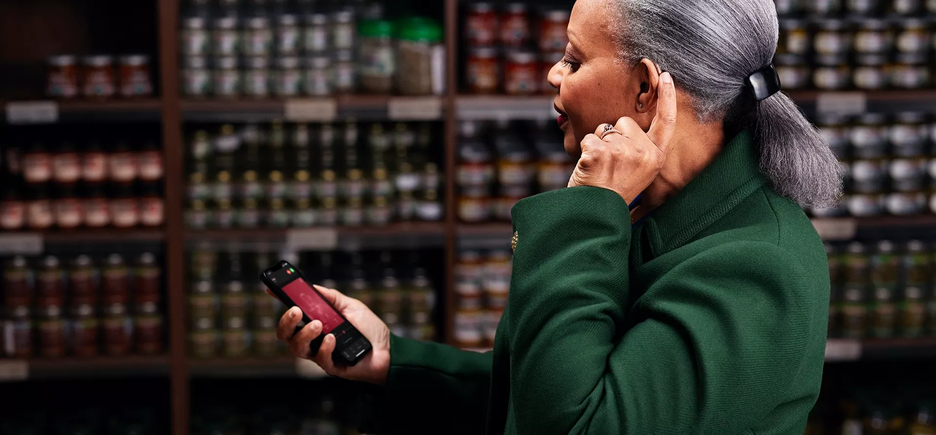 Frau mit gekoppelten Hörgeräten und ihrem Smartphone